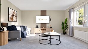 A modern living room with a sofa, a coffee table, a TV, and a window with curtains. - Nr Edinburgh/Rosyth Dockyard Stylish Home Sleeps 6 (Fife)