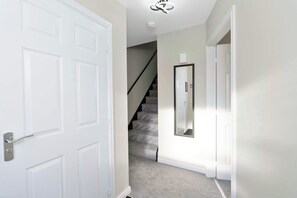 A hallway with a white door, a staircase, and a wall-mounted mirror. - Nr Edinburgh/Rosyth Dockyard Stylish Home Sleeps 6 (Fife)