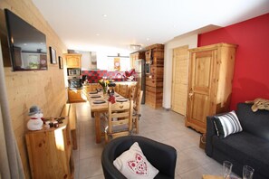 Ein gemütliches Wohnzimmer mit einer schwarzen Ledersofa und einem Holzesstisch für vier Personen.