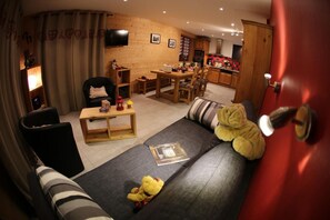 Ein gemütliches Wohnzimmer mit einer Couch, einem Esstisch und einer Küche im Hintergrund.