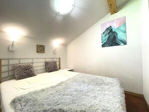 Ein Schlafzimmer mit einem Bett, weichen Kissen, einem Bild an der Wand und einer Deckenleuchte.