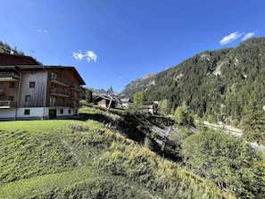 Ein Berghotel mit mehreren Balkonen, einer Seilbahn und einem bewaldeten Hintergrund.