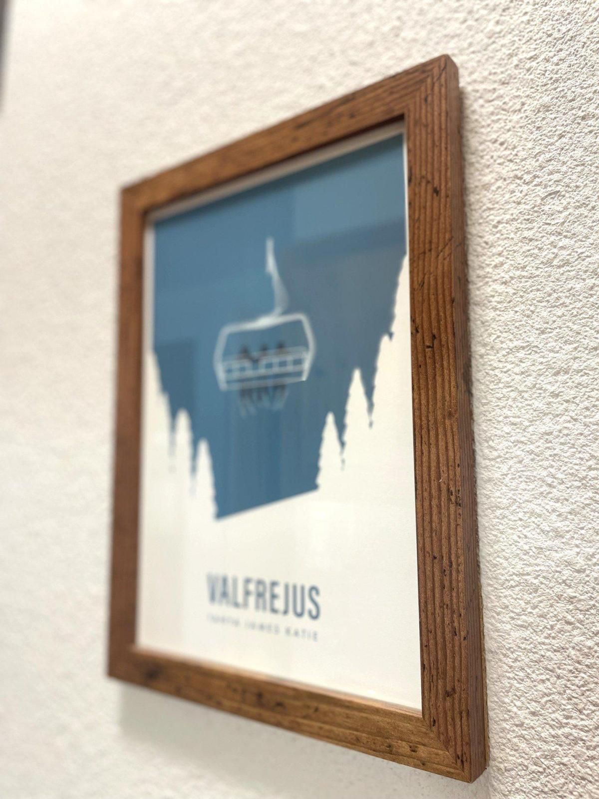 A framed picture with a mountain silhouette and the text 'VALFREJUS' on a textured wall.