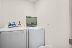 A laundry room with two washing machines, a dryer, and a Samsung microwave on top of one machine. - New 4BR Home | Ideal for Families & Teams (Dayton)