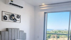 A bedroom with a bed, a large window, and a view of the outdoors. - Santa Marta apartment with ocean view, direct access to the beach, swimming pools, restaurant (Magdalena)