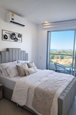 Een slaapkamer met een bed, een groot raam en uitzicht op de omgeving.
