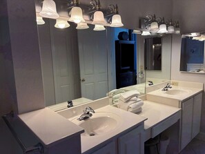 Casa de banho com duas pias, um espelho e um porta-toalhas.