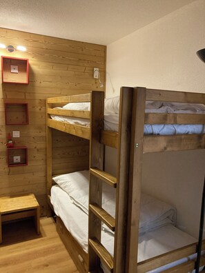 Ett rum med en våningssäng, träväggar, ett litet bord och en hylla med en röd ram.