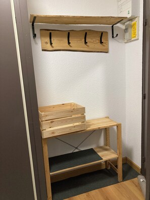 A corner room with a wooden bench, a shelf with hooks, and a power outlet on the wall. - Skis on!! Apartment for 5–6 people Val Thorens Olympic 204 (Les Belleville)