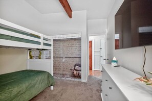 Een slaapkamer met stapelbedden, een bureau en een televisie.