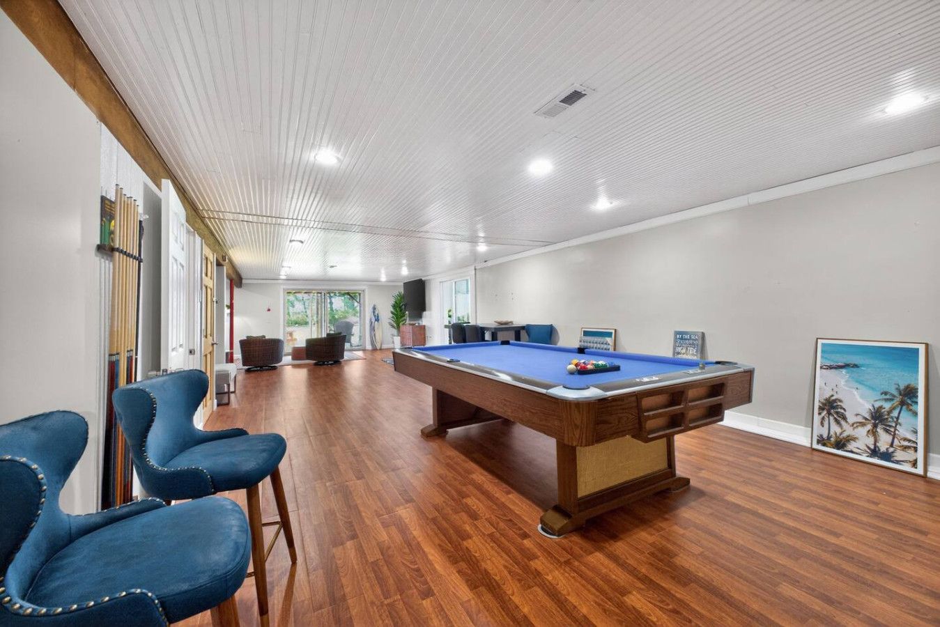 Una mesa de billar en una habitación con piso de madera y techo alto.