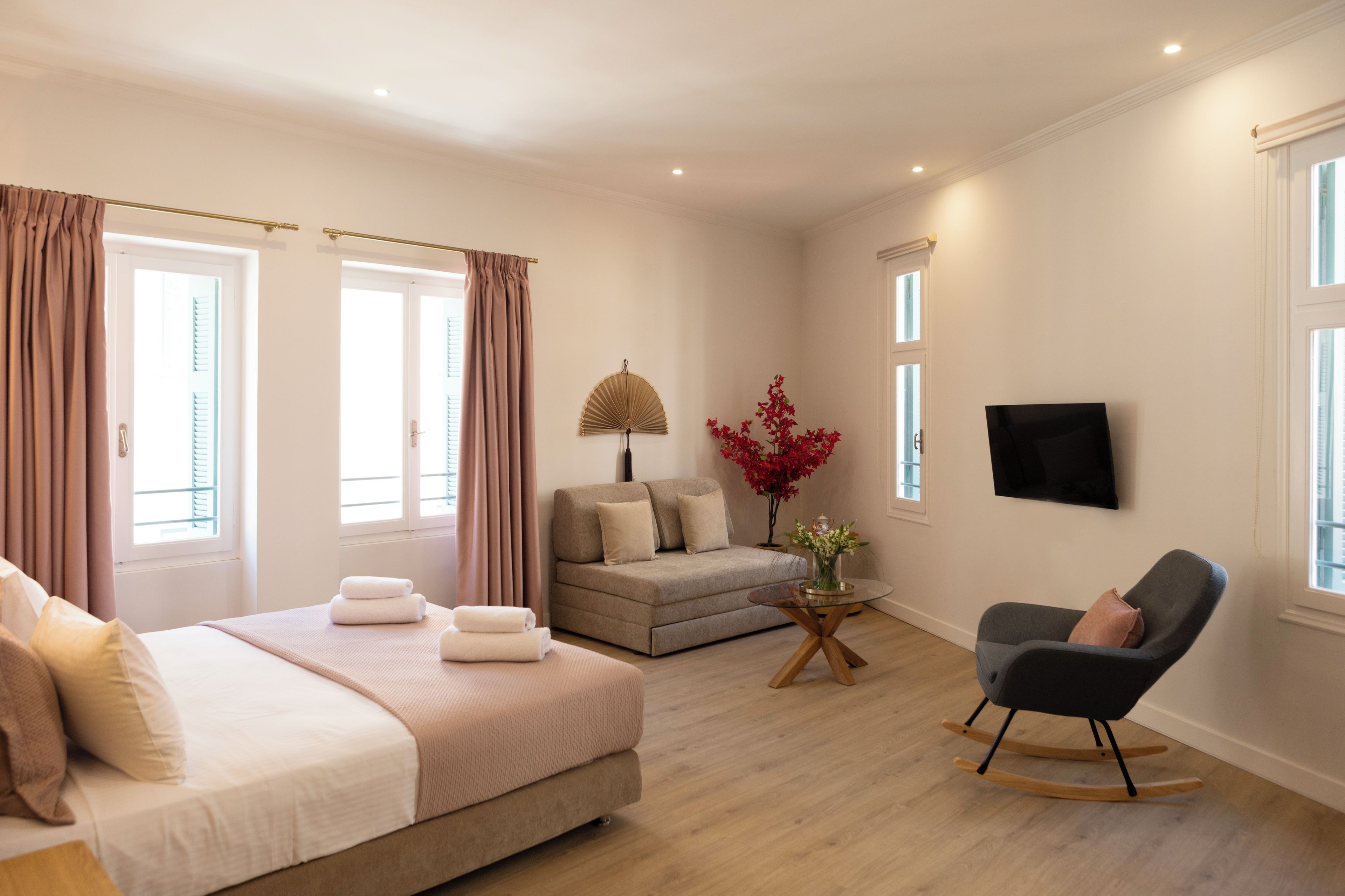 A hotel room with a bed, a sofa, a chair, a small table, and a TV.