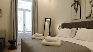 Une chambre d’hôtel avec un lit, une table de chevet, un miroir et une fenêtre avec des rideaux.