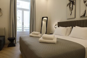 Una habitación de hotel con cama, mesita de noche, espejo y ventana con cortinas.