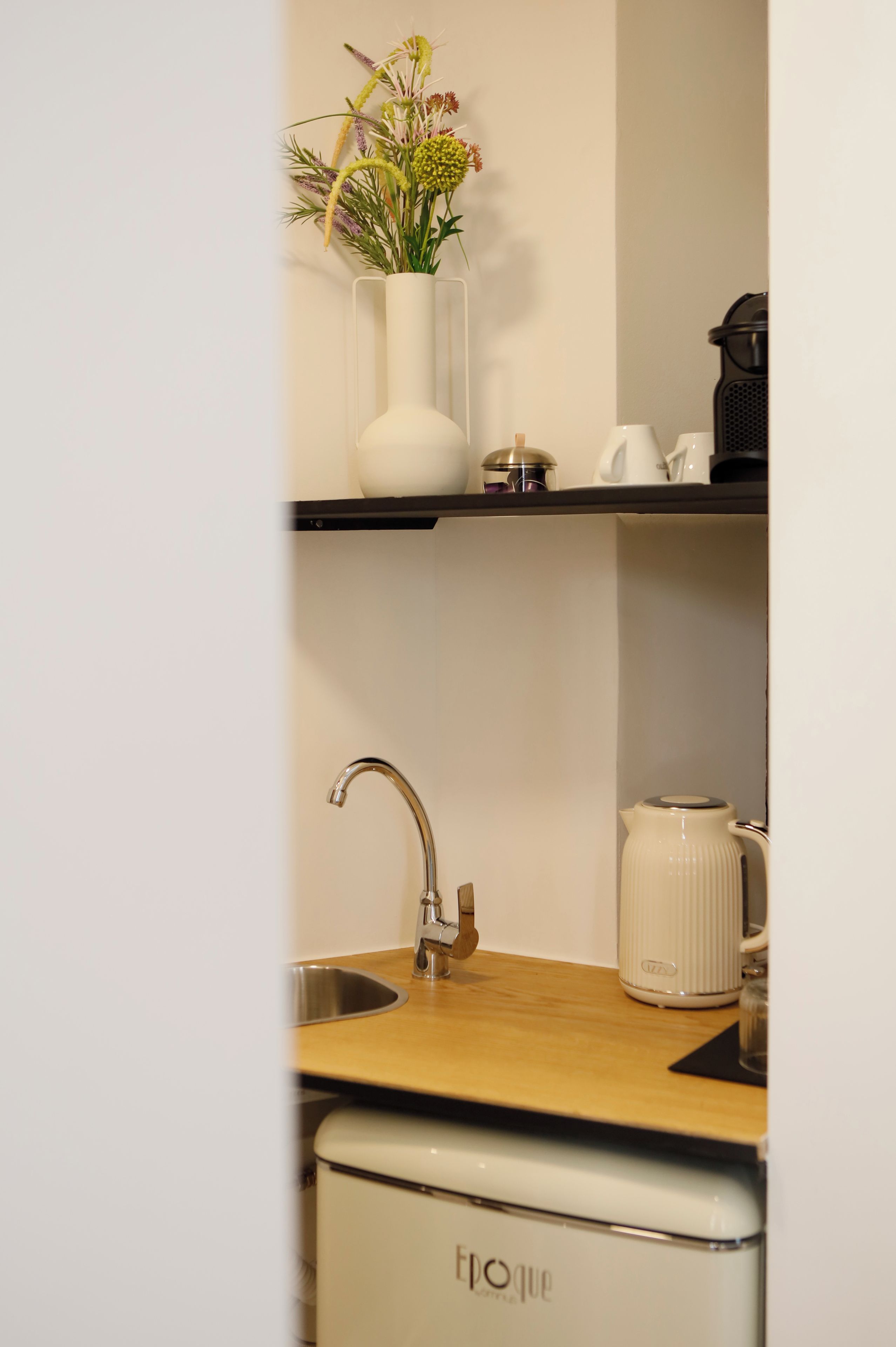 Een keuken met een roestvrijstalen spoelbak, een witte koffiezetapparaat en een witte vaatwasser.