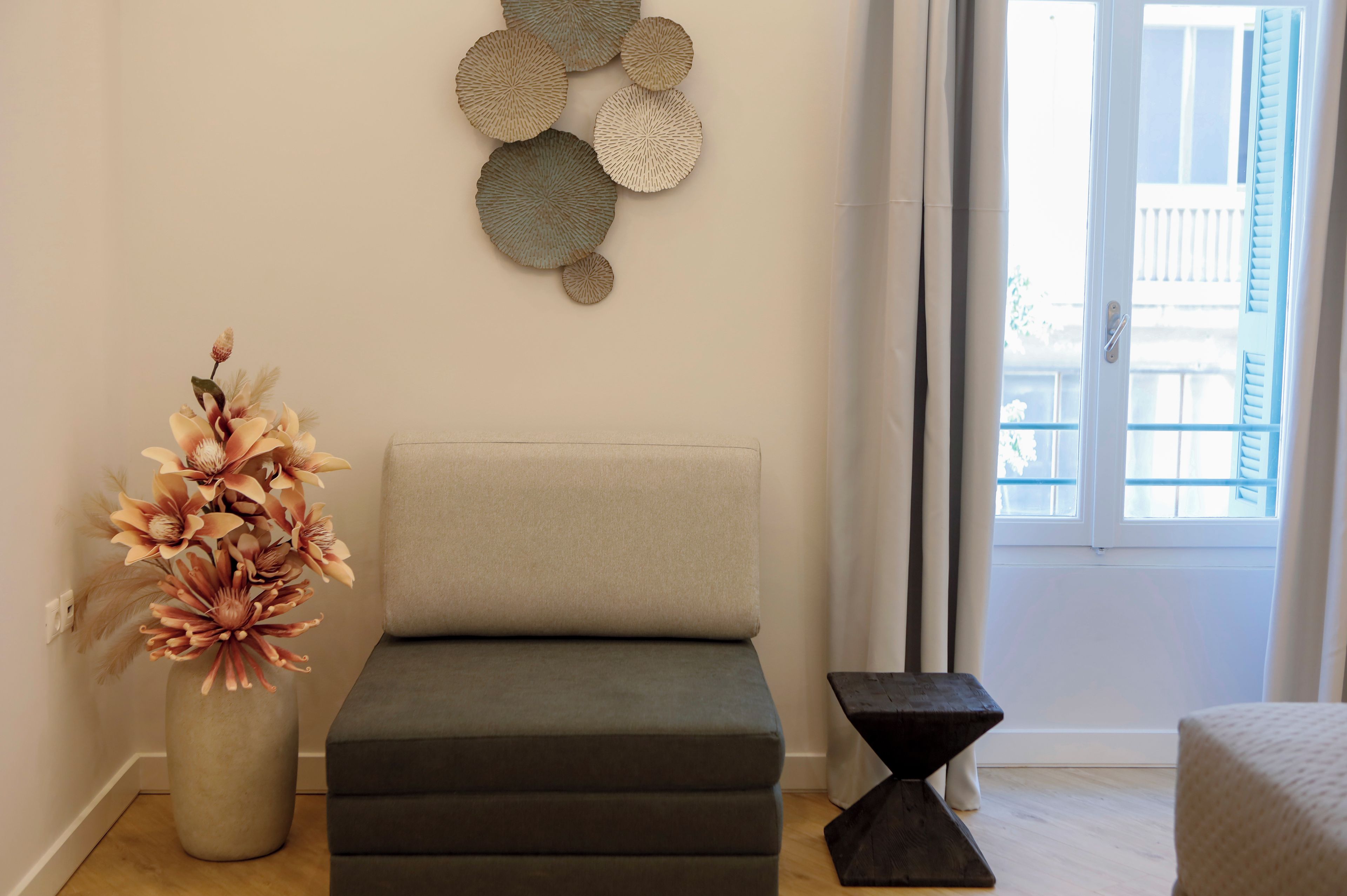 Una sala de estar moderna con un sofá, un adorno de pared y un florero con flores.