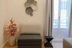 Una sala de estar moderna con un sofá, un adorno de pared y un florero con flores.