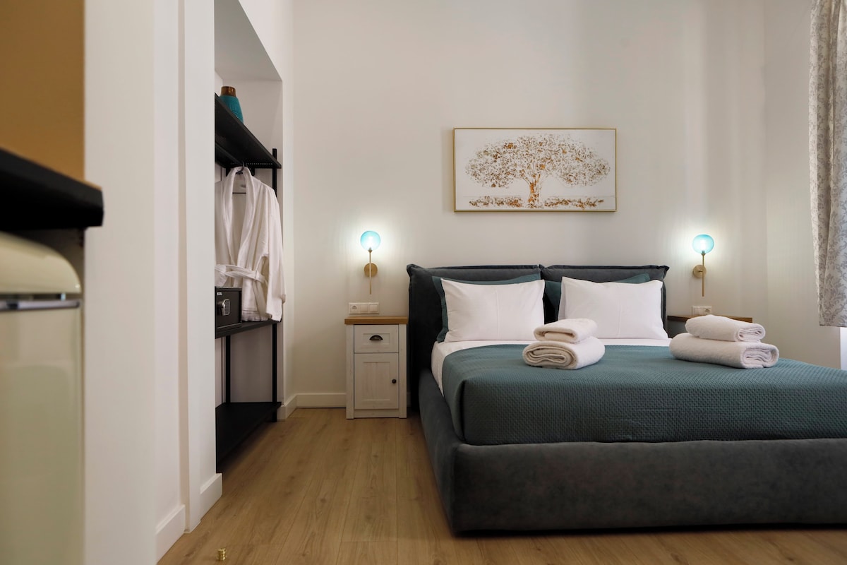 Un dormitorio con cama, lámparas de noche, mesita de noche, armario y un cuadro en la pared.