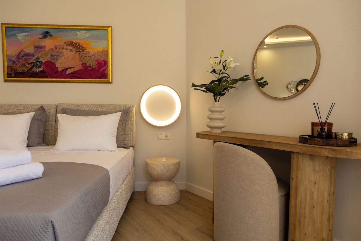 Habitación de hotel con cama, mesita de noche, espejo y un cuadro en la pared.