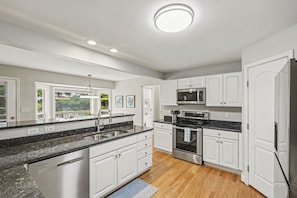 A modern kitchen with white cabinets, stainless steel appliances, and a granite countertop. - Freshly Renovated 4 Bedroom Home In Centerville OH (Dayton)