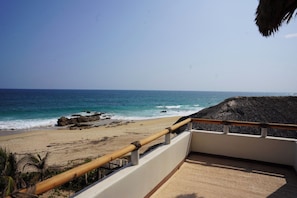 A beach view from a balcony with a railing, overlooking the ocean and a sandy shore. - Pacific Dreams Hotel Suites  (Agua Blanca, Cozoaltepec)