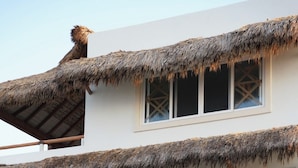 A multi-story building with thatched roofs and wooden railings. - Pacific Dreams Hotel Suites  (Agua Blanca, Cozoaltepec)