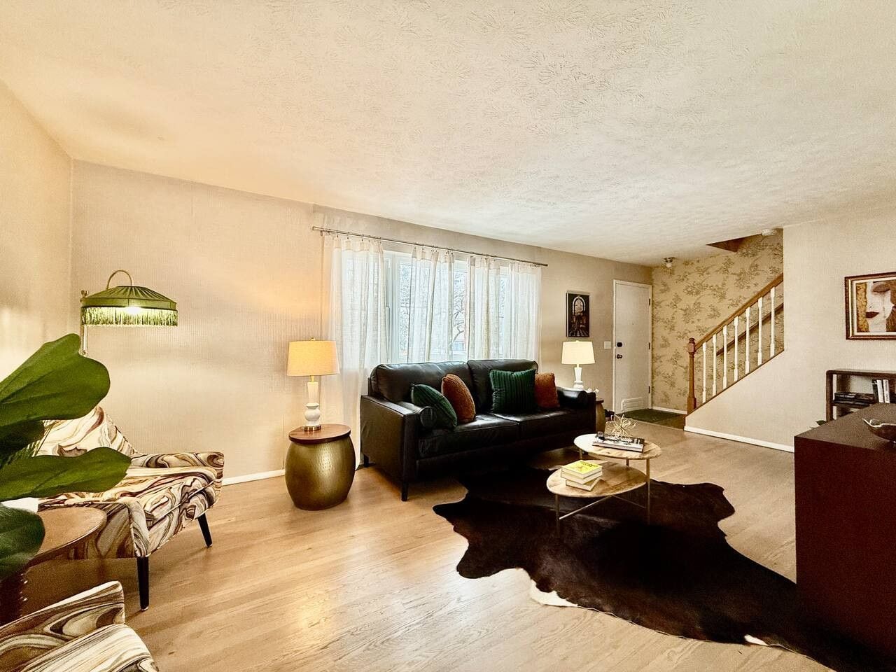 Un salon avec un canapé, une table basse, une lampe et un escalier en arrière-plan.