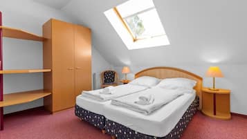 A bedroom with a bed, two bedside lamps, a wardrobe, and a skylight.