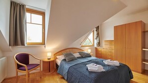 A bedroom with a bed, a chair, a wardrobe, and a window.