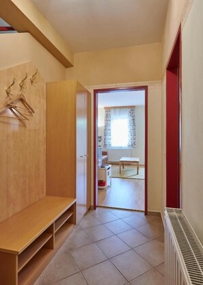 A hallway with a bench, a radiator, and a door leading to a room with a window.