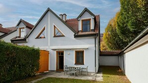 A residential property with a covered patio, a small lawn, and a white exterior wall.