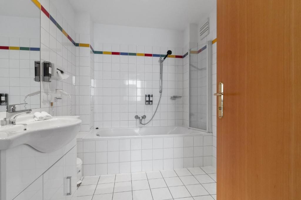 A bathroom with a white sink, mirror, and shower area.