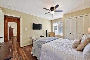 A bedroom with a bed, a chair, a television, and a ceiling fan. - Point of View l 3BR - Dock & Big Views (Northport)