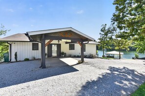 A lakeside house with a covered porch and a gravel driveway. - Point of View l 3BR - Dock & Big Views (Northport)