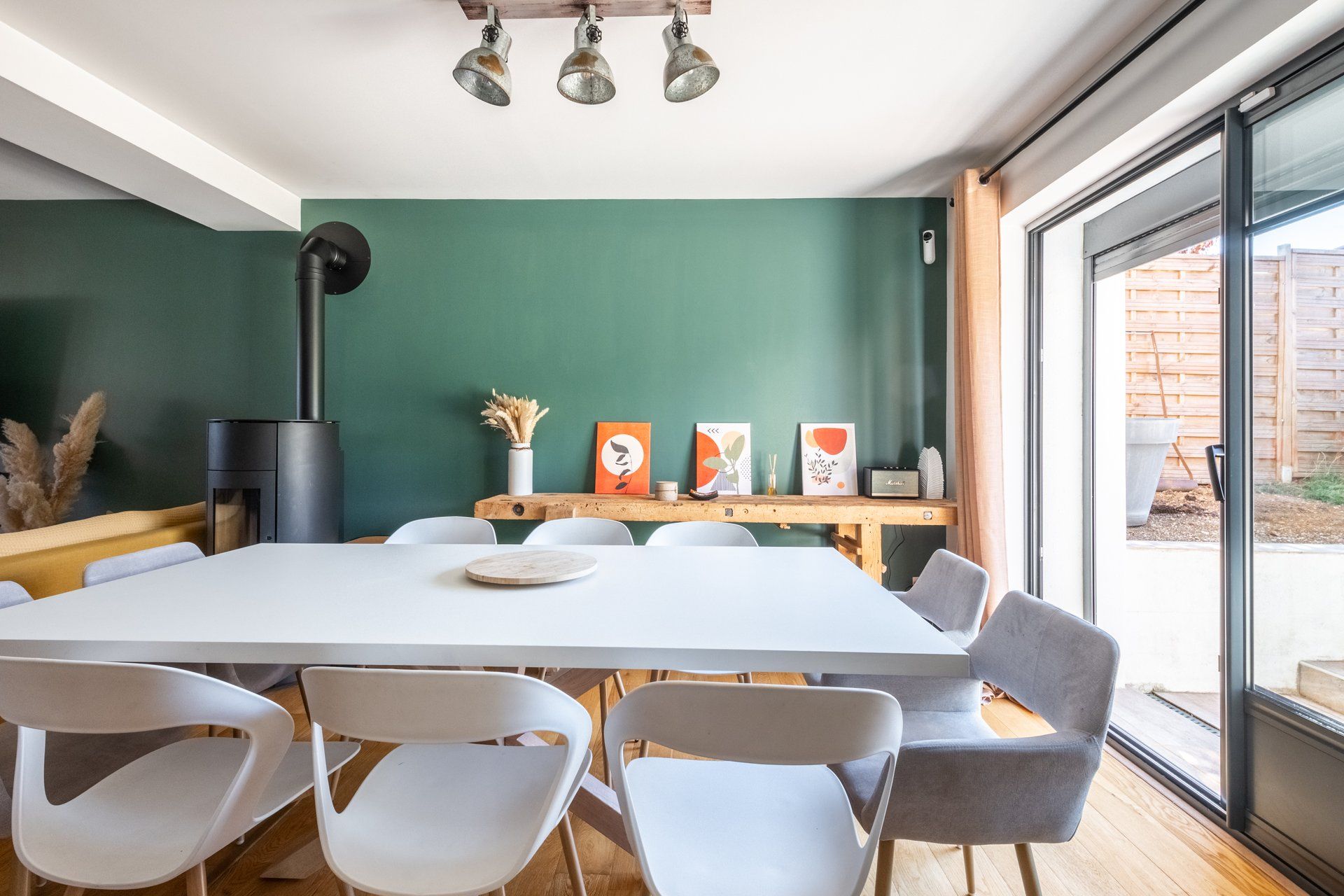 Une salle de conférence avec une grande table, des chaises blanches et des œuvres d’art accrochées au mur.