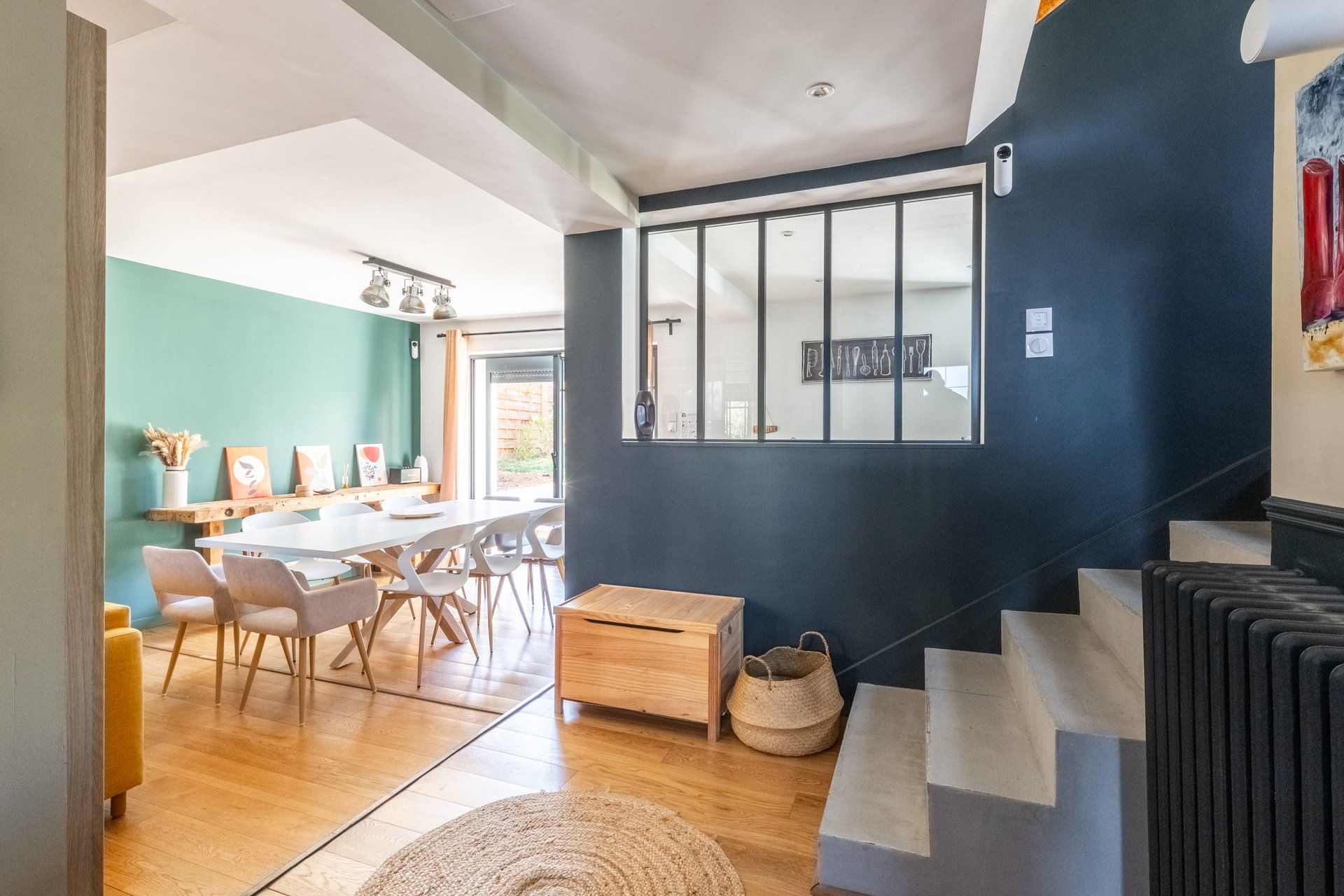 Ein modernes Interieur mit Essbereich, Treppe und Blick durch ein Fenster.