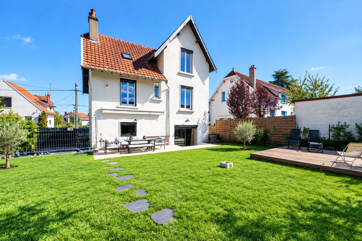 A two-story house with a well-maintained lawn, a patio with seating, and a small garden area.