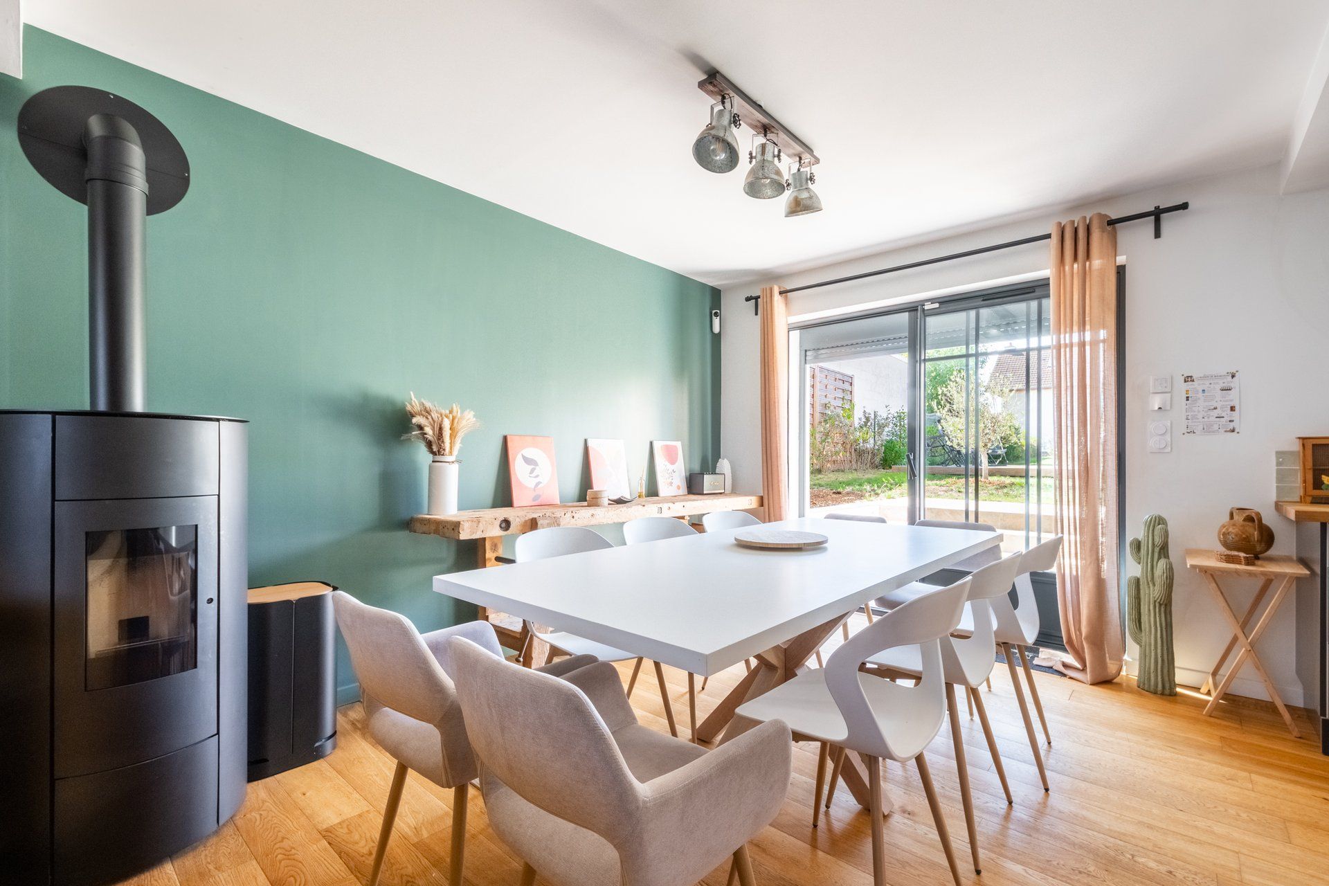 A modern kitchen with a central island, a built-in stove, and a dining area with a white table and chairs.
