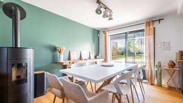 A modern kitchen with a central island, a built-in stove, and a dining area with a white table and chairs.