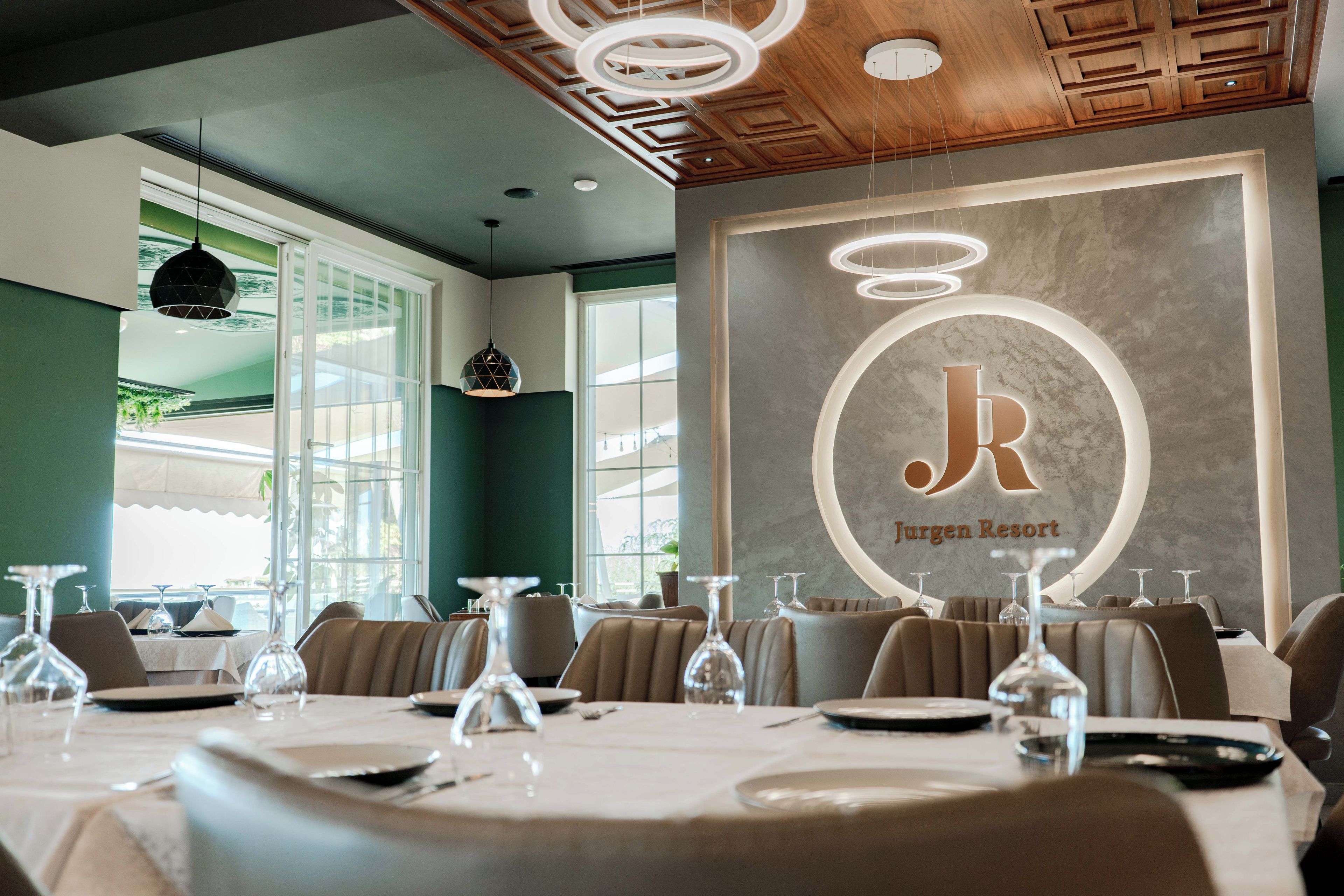 Un interior de restaurante con mesas dispuestas para comer, un letrero iluminado grande y un diseño de techo moderno.