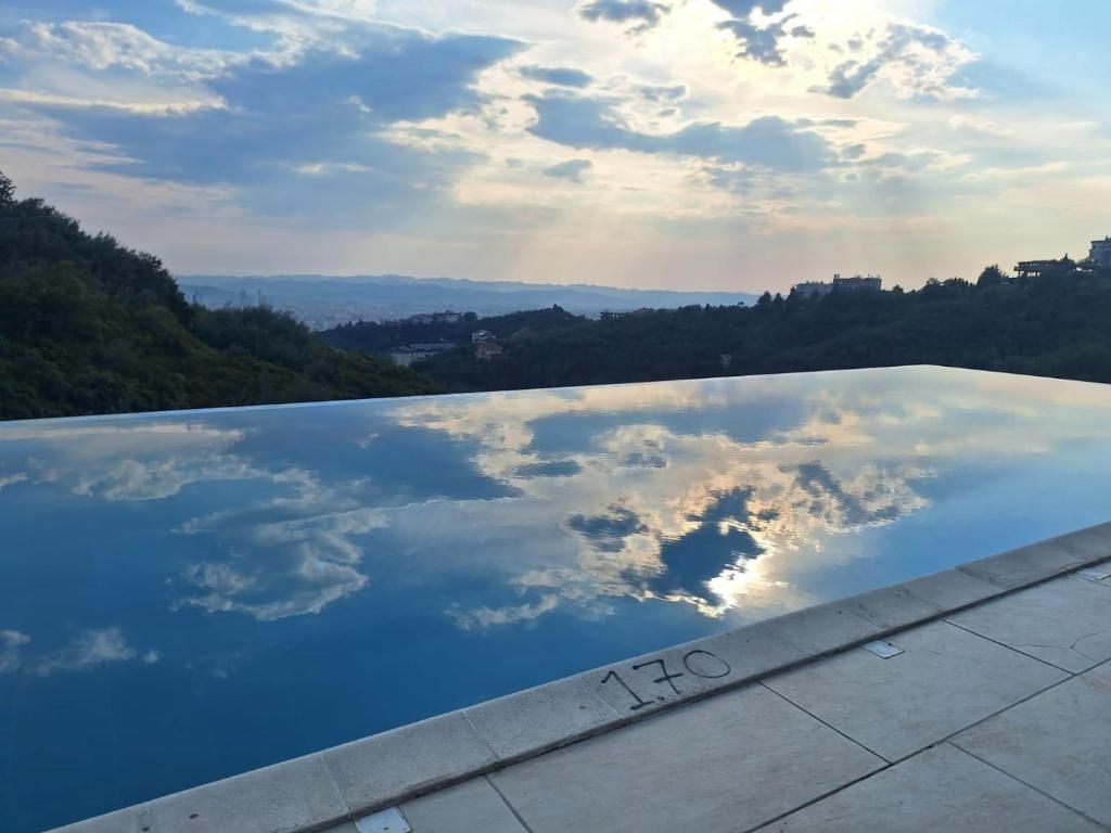 Una piscina con vistas despejadas al paisaje circundante, incluyendo colinas y el perfil distante de una ciudad.