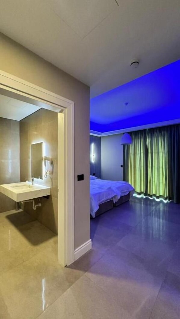 A hotel room with a bathroom, a bed, and a view of the outside.
