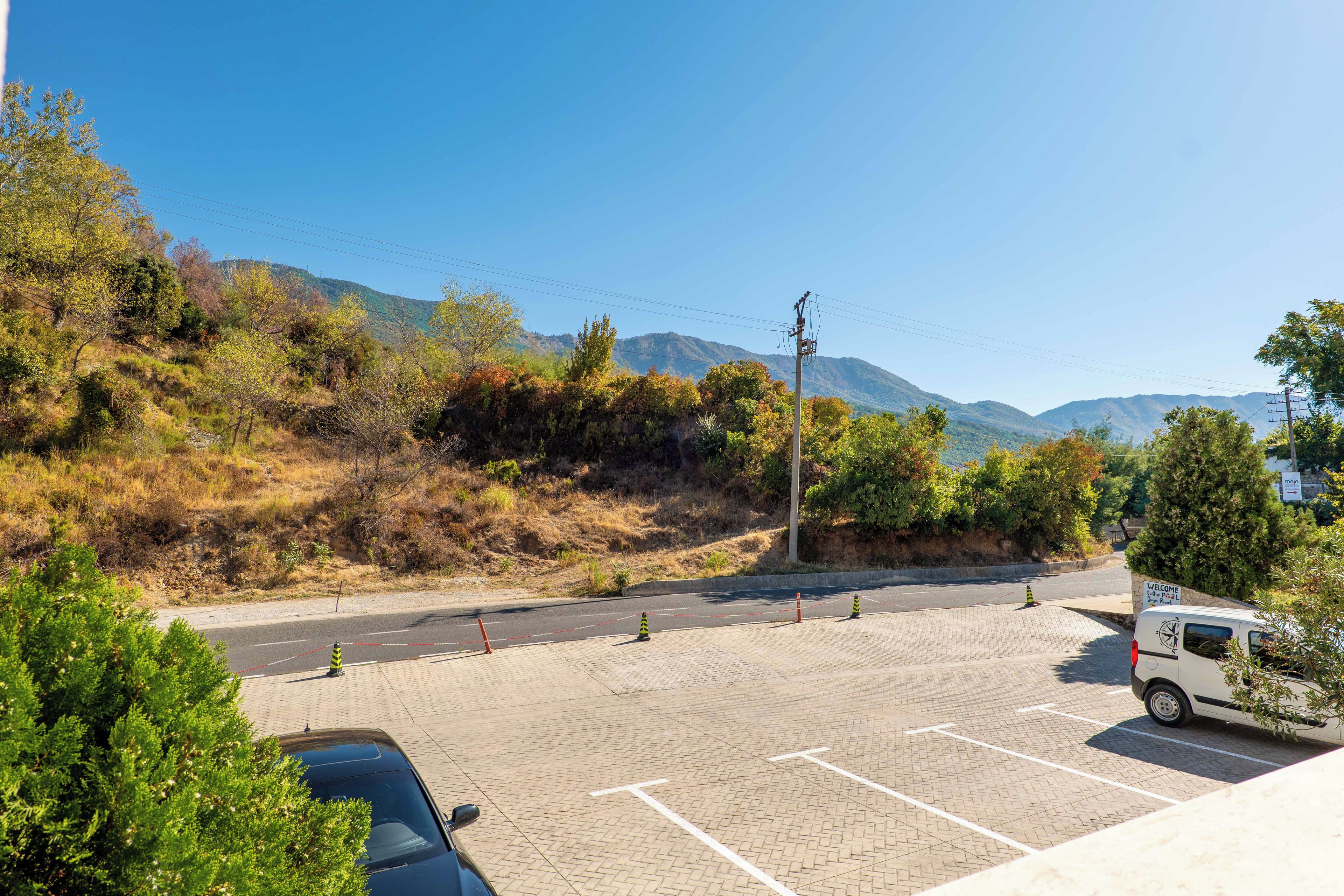 A parking lot with marked spaces, a white van, and a mountainous backdrop.