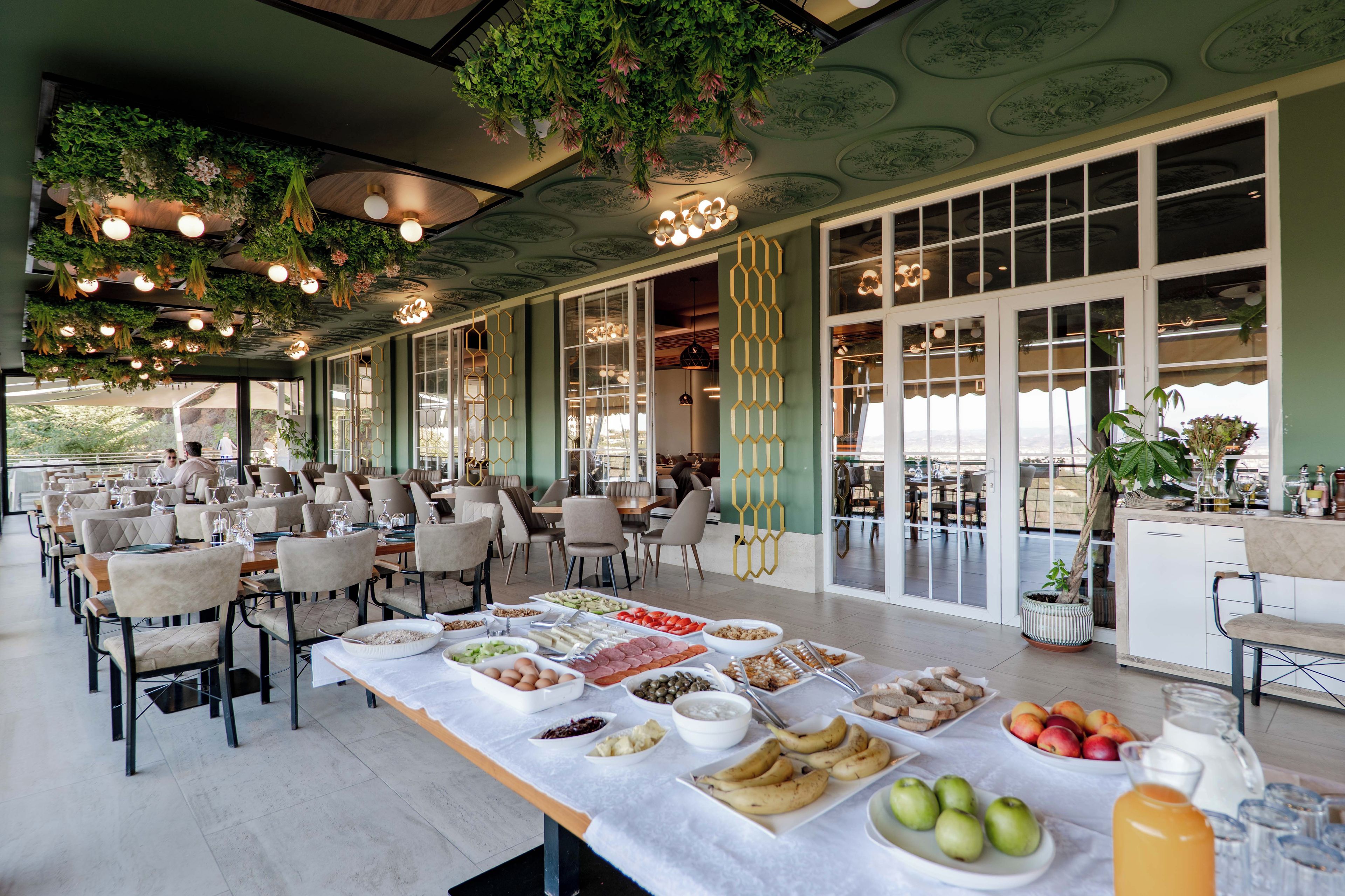 A dining area with tables set for a buffet, featuring a variety of food items and a beverage pitcher.