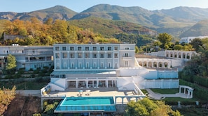 A large hotel with multiple buildings, a swimming pool, and a mountainous backdrop.