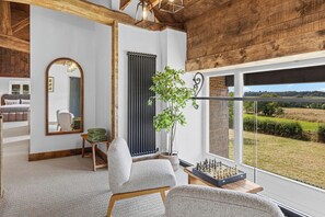A room with a large window, a radiator, a plant, and a chessboard. - The Barn, an Exceptional Luxurious Retreat (Newburgh)