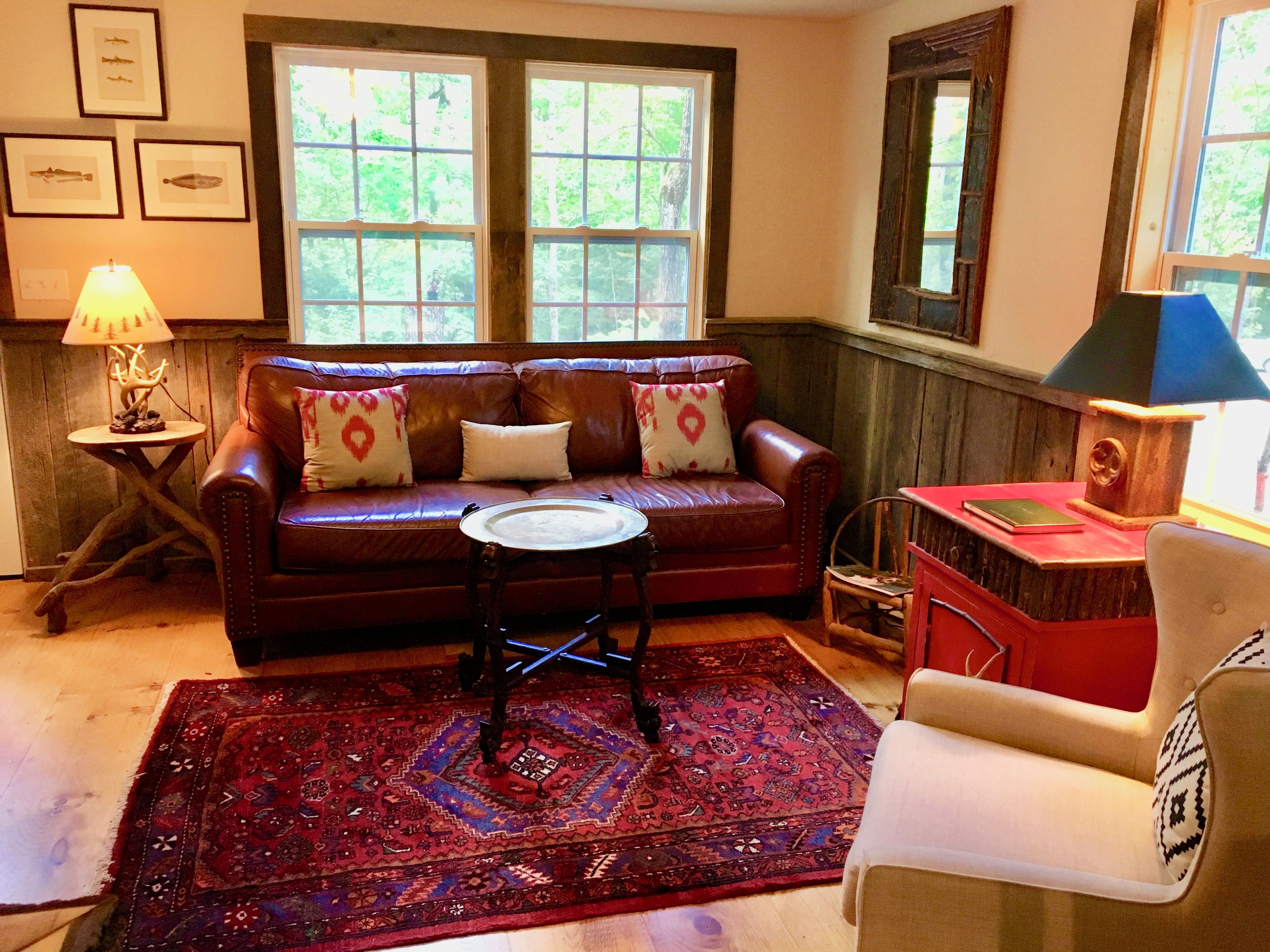 A cozy living room with a leather sofa, a patterned rug, and a wooden side table with a lamp.