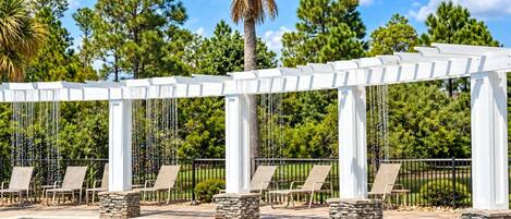 A pool area with lounge chairs and a pergola structure.