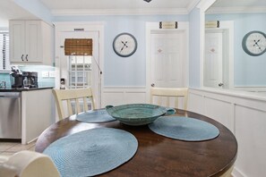Un coin repas avec une table ronde, des chaises et une horloge au mur.
