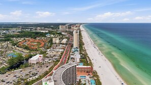 A coastal cityscape with a beachfront hotel, a marina, and a highway. - Coastal Dreams | Golf Cart | 11 Pools | Beach Access | Sleeps 7 (Panama City Beach)